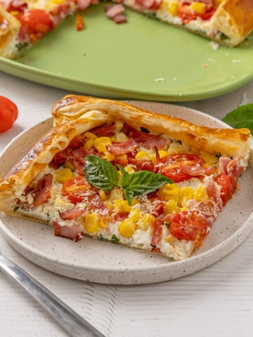 A piece of Sweet Corn, Tomato & Turkey Bacon Galette on a plate.