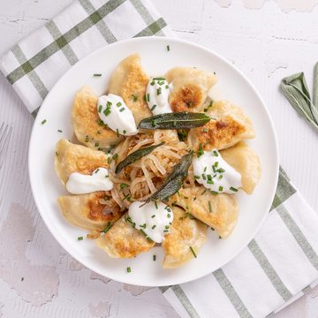 Pumpkin pierogies with brown butter and sage on a plate.