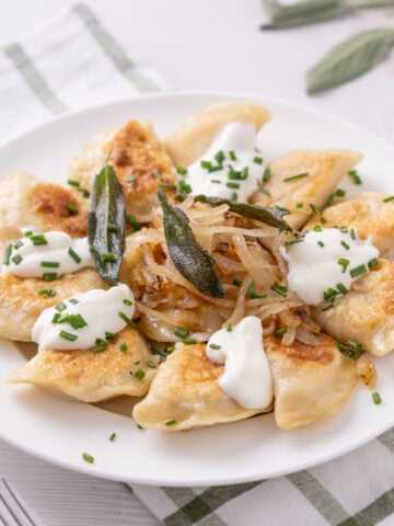 Pumpkin Pierogies with brown butter and sage on a plate.